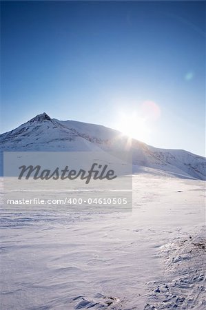 A winter landscape with a mountain and blue sky