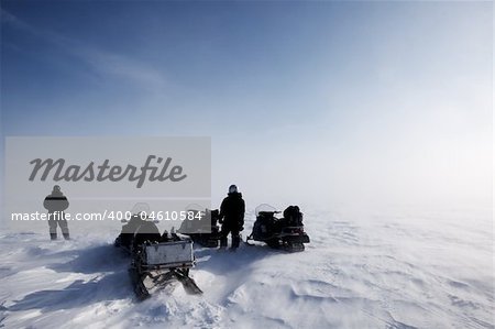 A blowing snow landscape with three snowmobiles on an expedition