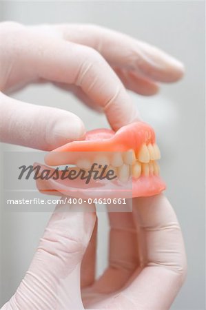 A doctor holding in her hand artificial teeth.