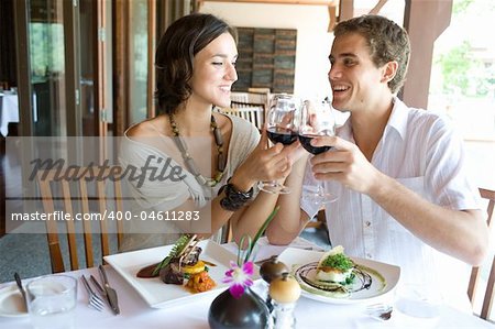 A young couple sitting together in a restaurant holding hands