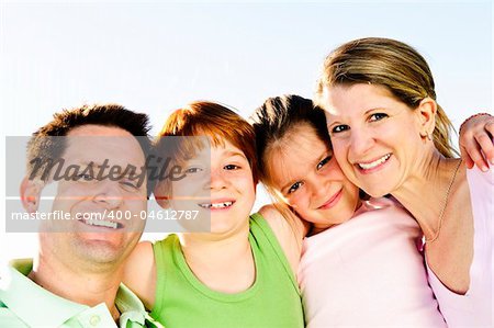 Portrait of happy family of four hugging and smiling