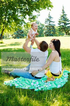 Family sitting  in the summer park  and playing