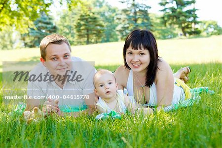 Mom, dad and baby lying in the grass