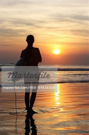 Surfer with board going into the sea at dawn