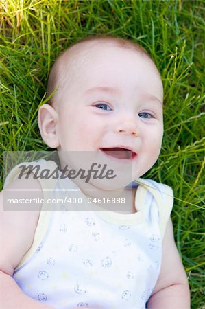 Portrait of a laughing baby lying in the grass