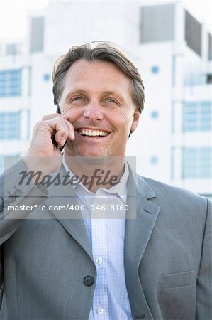 A colour portrait of a handsome smiling businessman enjoying a friendly chat on his cellphone.