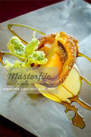 A decadent dessert of apple, peach tempura cobbler with sweet sauces on a stainless steel platter.