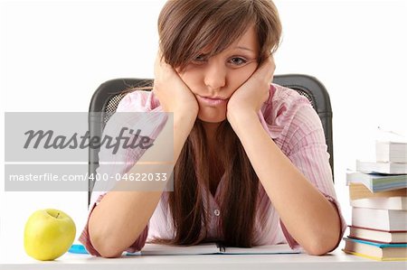 Teenage girl studying with textbooks looking unhappy