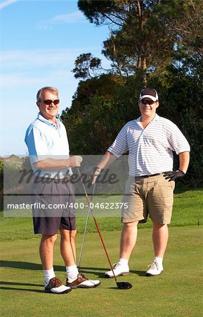 Young male golfer with his senior father ready to tee off on a beautiful summer day