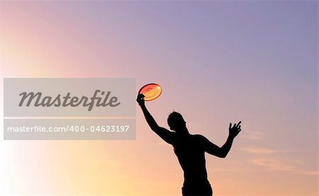 silhouette of a man catching a frisbee