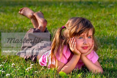 Little girl lying on the grass in the park, dreaming of something