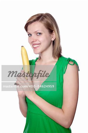 Pretty girl in a green dress is holding a banana as a gun, isolated on white