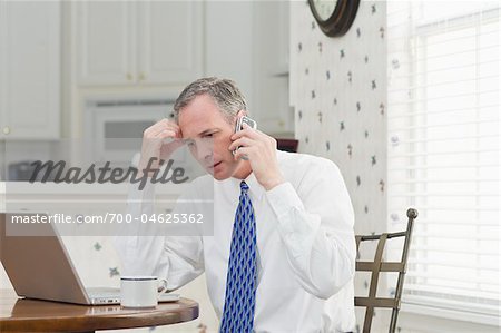 Businessman with Cell Phone and Laptop at Home