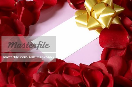 Red rose petals in heart shape with a copy space blank note