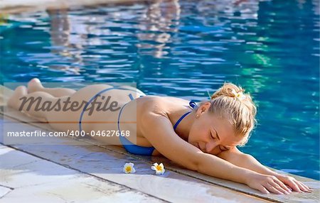 Beautiful blonde girl in hotel swimming pool with flowers