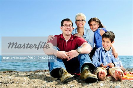 Happy family sitting on towel at sandy beach
