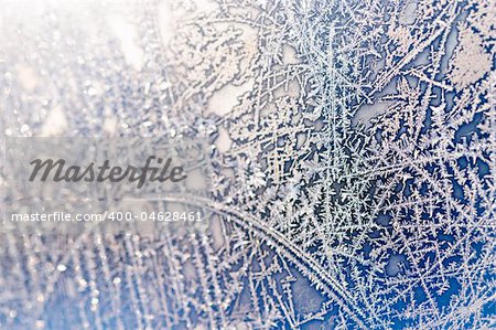 Extreme close-up shot of frozen window with beautiful natural ice ornament (partial blurred)