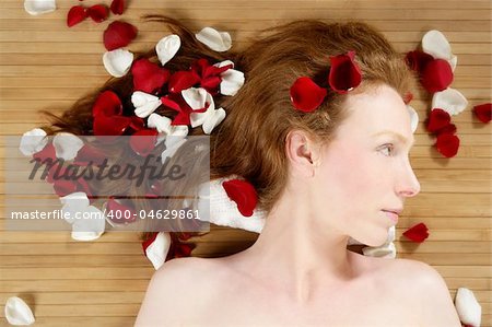 Redhead beautiful woman with colorful rose petals on hair