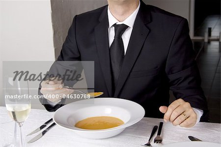 Business man is having lunch at a frensh gourmet restaurant. He is having lobster soup.