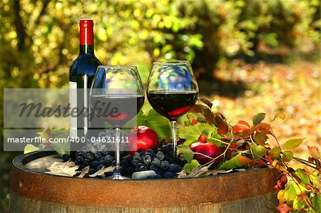 Glasses of red wine on old barrel with autumn leaves