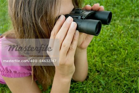 Young woman holding binocular lenses on grass