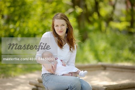 Young mother is holding her newborn baby in the arms