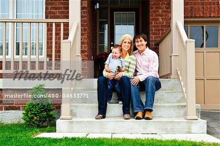 Young family sitting on front steps of house