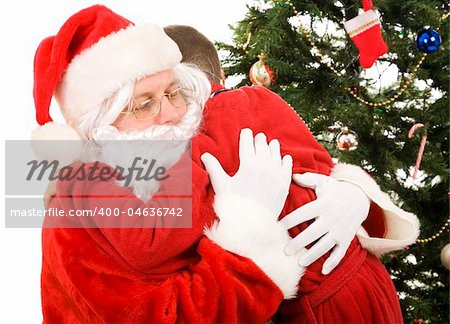 Santa getting a big hug from a child on Christmas morning.