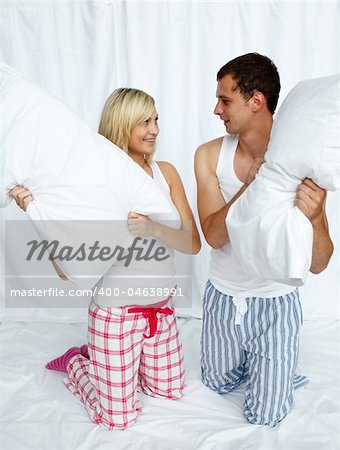 Young couple having a pillow fight in bedroom