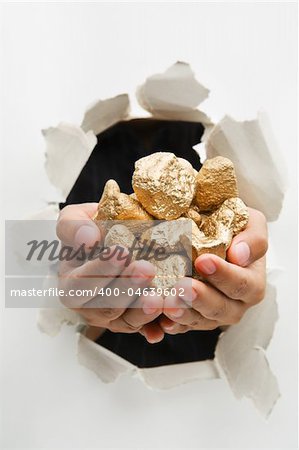 Hand breakthrough wall holding lumps of golden nuggets means breaktrhough in finance or similar things - one of the breakthrough series