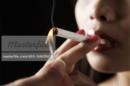 Woman start smoking with somebody else fingers holding the burning match