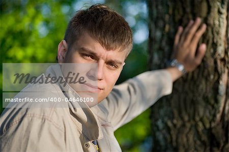 Close-up portrait of young man holding from a tree