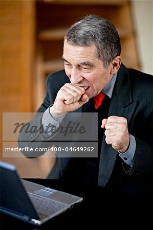 A businessman recoils from his laptop computer in horror.