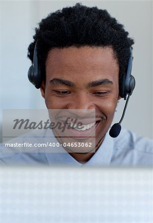 Smiling Afro-American businessman talking on a headset in a call center