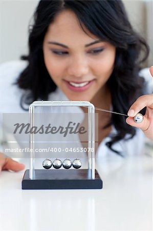 Businesswoman playing with Newton balls in office