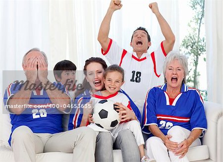 Family watching a football match in television at home