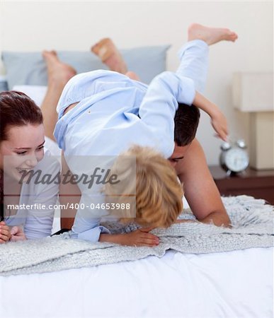 Little son playing with his parents in bed