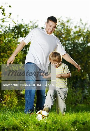 Game in football of father and son on a summer lawn