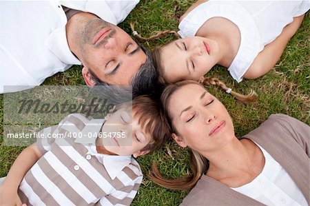Parents and children sleeping in a park with heads together