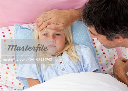 Father taking his daughter's temperature lying in bed