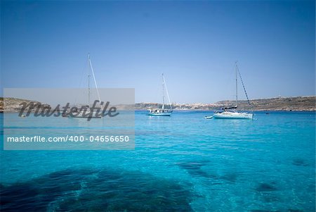 Boats moored in the crystal clear waters of the Blue Lagoon on the island of Comino in Malta.