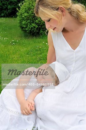 Young mother and daughter resting in meadow