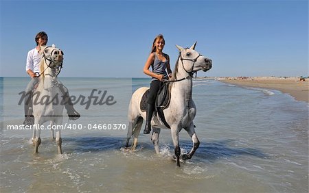 father and daughter with arabian and camargue horses on the beach