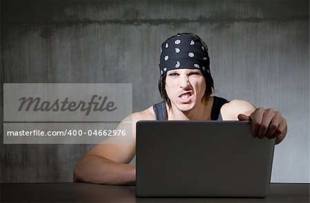 Internet pirate holding onto silver laptop computer