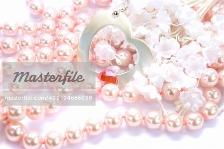 Necklace with pink stone on it,pearls and fabric flowers on white background.