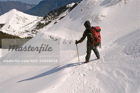 Man hiking on snow white mountain path.