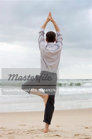 Businessman doing relaxation exercises on a beach