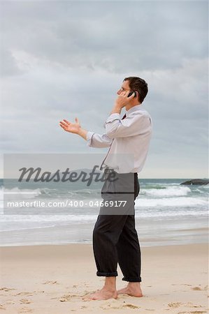 Businessman talking on cell phone on a beach while gesturing with his hand