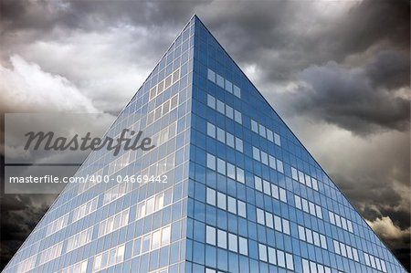 Blue office building with cloudy dark sky