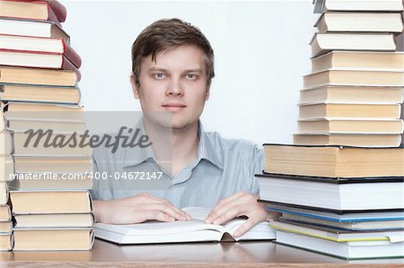 Young happy student reading book between books